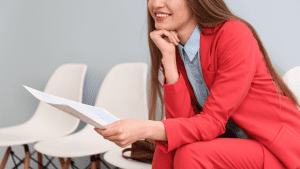 woman sitting down smiling with her resume in hand